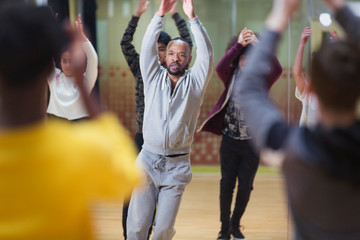 Focused male instructor leading dance class in studio
