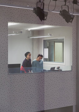 Teenage girl musicians recording music in sound booth