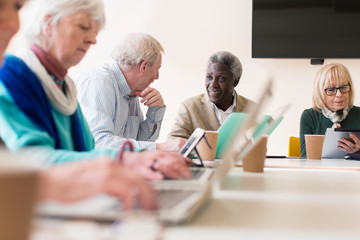 Senior business people talking, using laptops digital tablets in conference room meeting