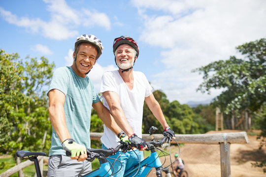 Portrait confident father and son mountain biking on sunny trail - Powered by Adobe