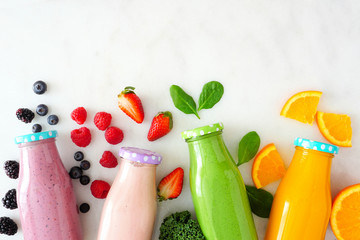 Assorted healthy fruit smoothies in bottles with ingredients. Top view against a white marble...