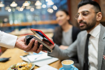 Businessman in cafe paying with smart phone contactless payment