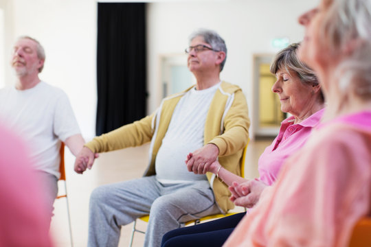 Serene active seniors holding hands, meditating