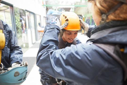 Woman helping friend with zip line helmet - Powered by Adobe