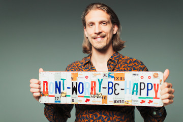 Portrait smiling young man holding  Dont Worry Be Happy  license plates