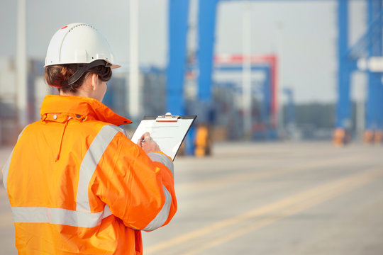 Female dock worker with clipboard at shipyard