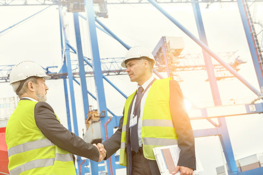 Dock managers shaking hands at sunny shipyard