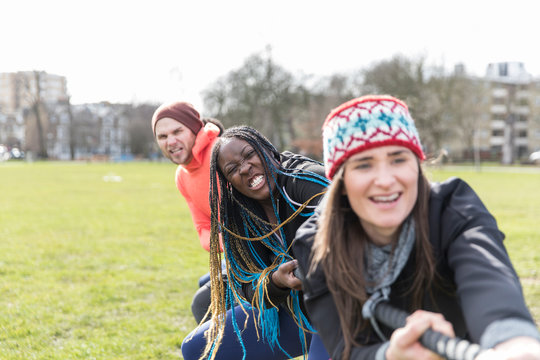 Determined team pulling rope in tug-of-war in park