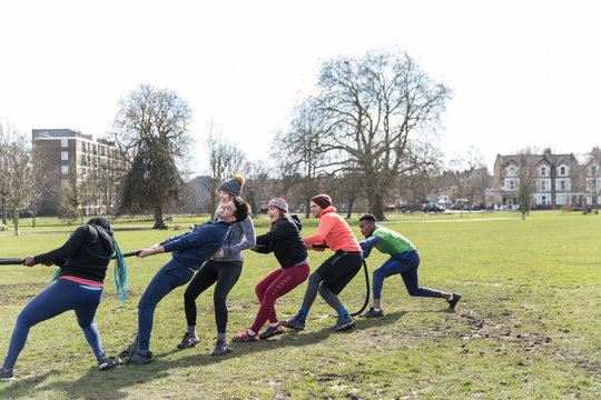 Determined team pulling rope in tug-of-war in park