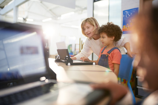 Teacher and schoolgirl using laptop