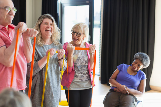 Happy Instructor And Active Seniors Exercising With Straps