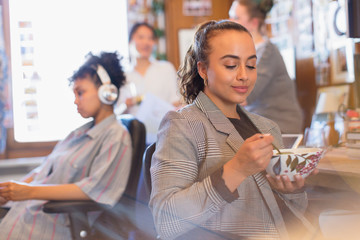 Creative businesswoman eating soup in office
