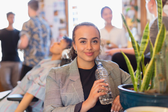 Portrait confident businesswoman drinking bottled water in office