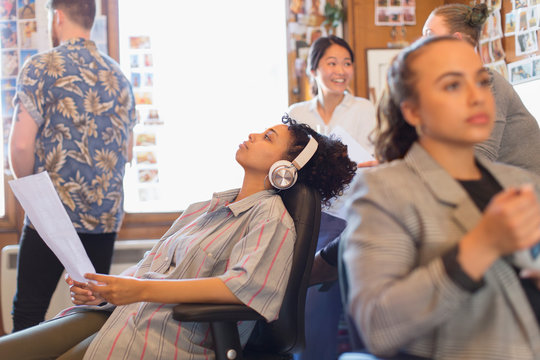 Creative businesswoman with headphones listening to music in office