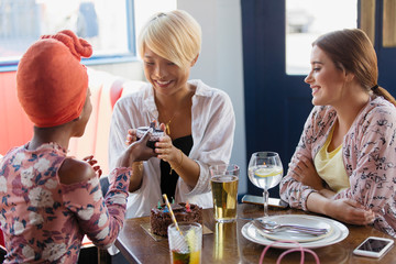 Young woman giving birthday gift to friend in restaurant