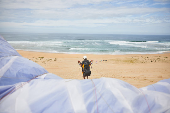 Paraglider with parachute on ocean beach