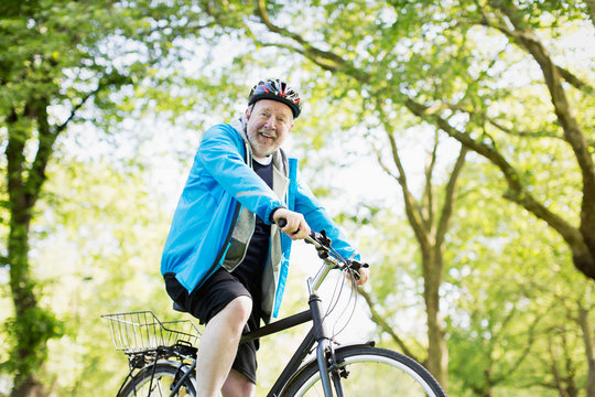 Portrait smiling active senior man riding bike in park