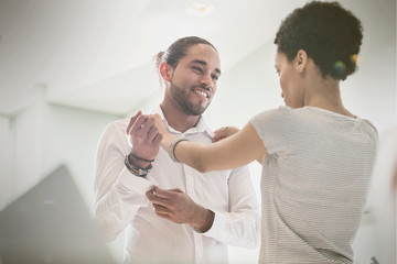 Woman helping boyfriend getting dressed, adjusting shirt collar