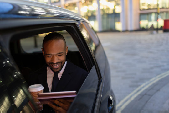 Businessman drinking coffee using digital tablet in crowdsourced taxi
