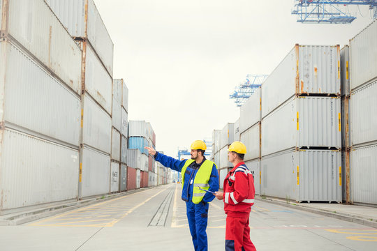 Dock workers talking among cargo containers at shipyard