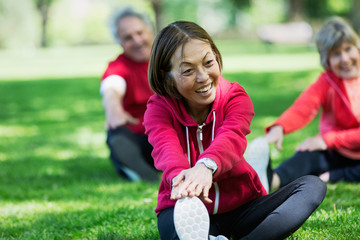 Happy active senior woman stretching leg in park