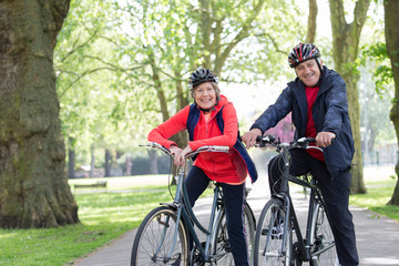 Portrait smiling, confident active senior couple riding bikes in park