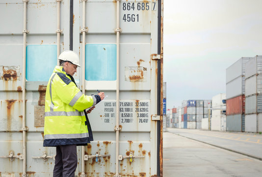 Dock worker checking cargo containers at shipyard