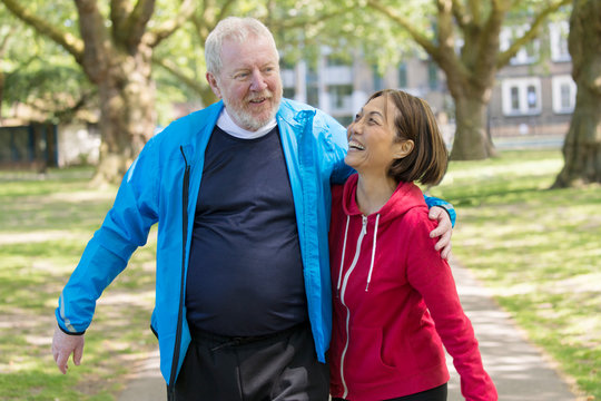 Affectionate active senior couple walking in park