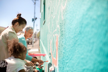 Female volunteers painting mural on sunny wall
