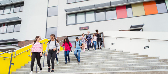 Junior high students leaving school building, descending steps