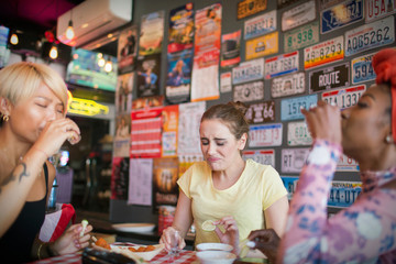 Young women friends taking tequila shots in bar