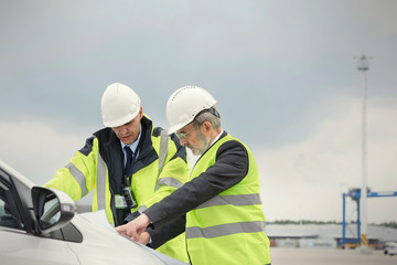 Dock worker and manager reviewing blueprint at shipyard