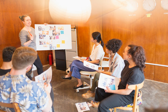 Creative designers brainstorming, reviewing photograph proofs in office meeting