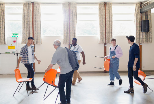 Men arranging chairs for group therapy in community center