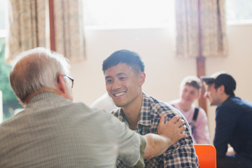 Smiling men talking in community center