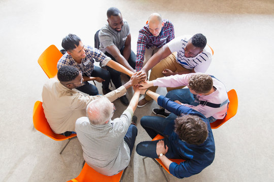 Men joining hands in circle in prayer group