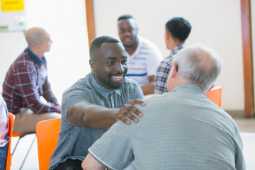 Smiling, happy man talking, comforting man in group therapy