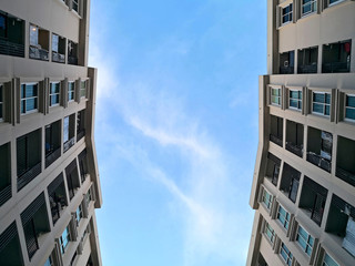 Low angle view of residential building condominium or apartment with blue sky and cloud background.