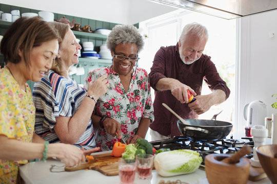 Active Senior Friends Cooking In Kitchen