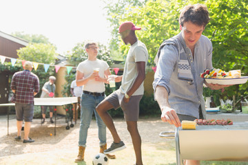 Male friends enjoying summer backyard barbecue