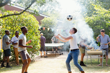 Male friends playing soccer and ping pong, enjoying backyard barbecue
