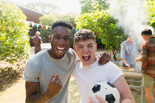 Portrait enthusiastic young men soccer ball cheering, enjoying back yard barbecue