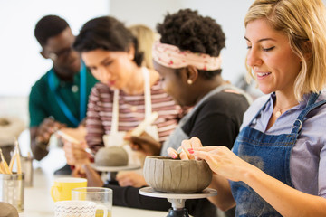 Woman making clay bowl in art class