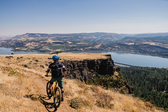 Man mountain biking, enjoying Columbia River view from cliff, Hood River, Oregon, USA