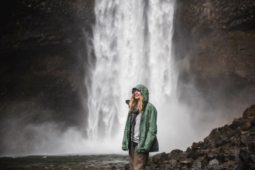 Smiling female hiker in rain jacket at waterfall, Whistler, British Columbia, Canada