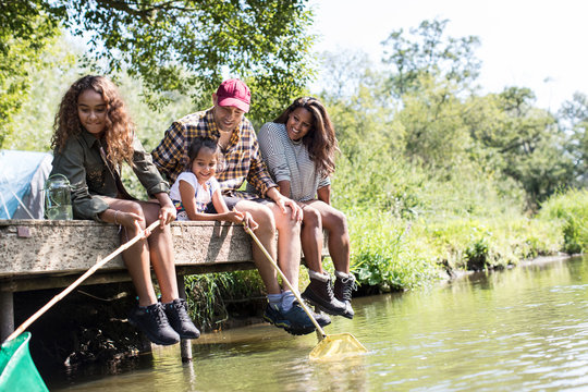 Happy family fishing from sunny riverside dock