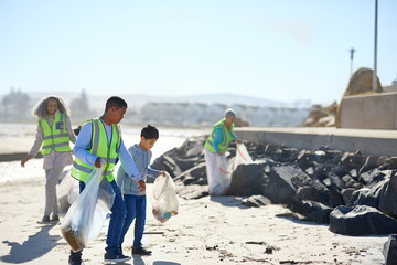 Father and son volunteers cleaning up litter on sunny beach