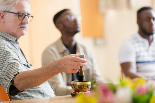 Man using singing bowl in meditation group - Powered by Adobe