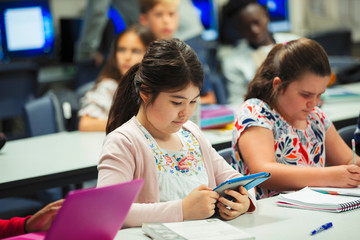 Focused junior high school girl student using digital tablet in classroom