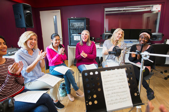 Womens choir with sheet music singing in music recording studio